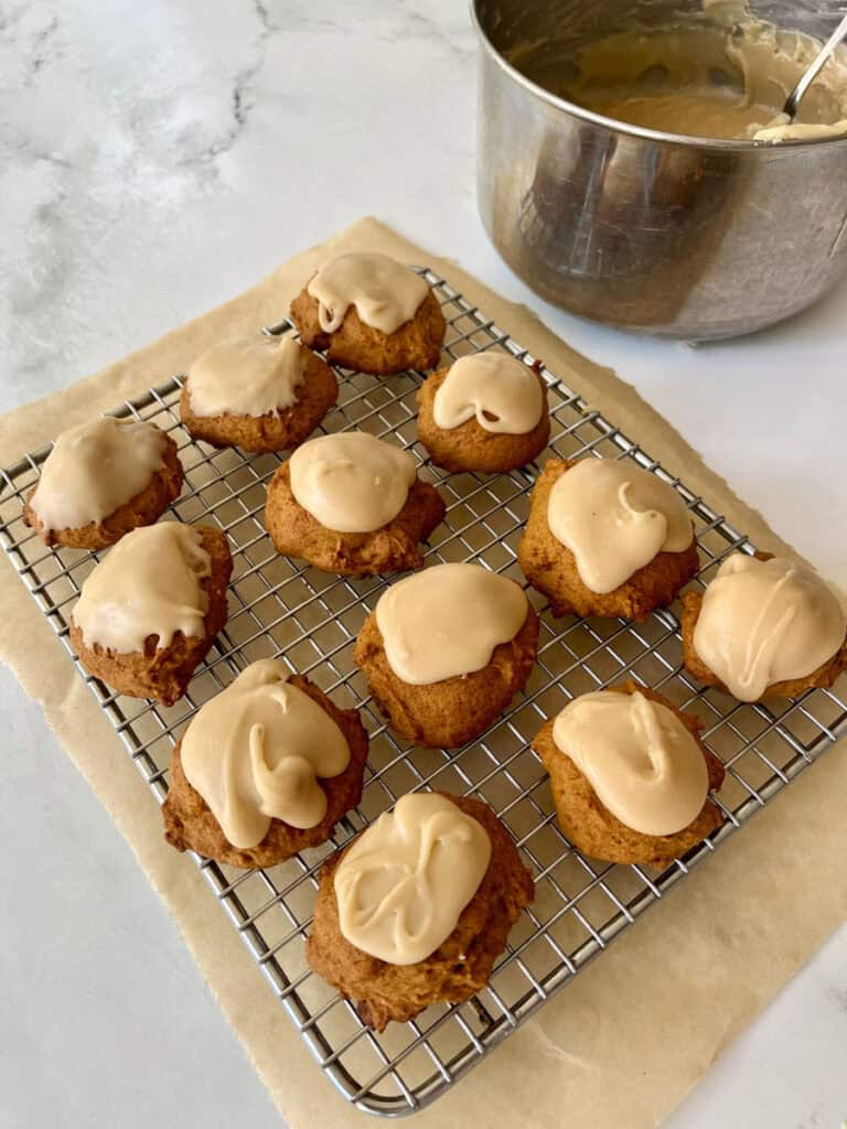 Old-fashioned soft pumpkin cookies with penuche frosting on a cooling rack.