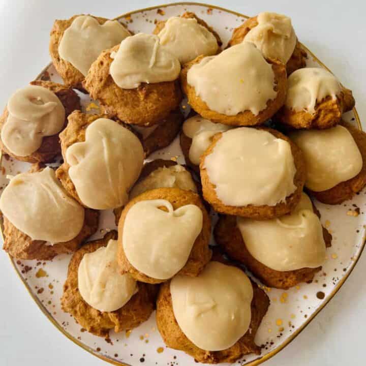 Soft pumpkin cookies with penuche frosting on a decorative plate.