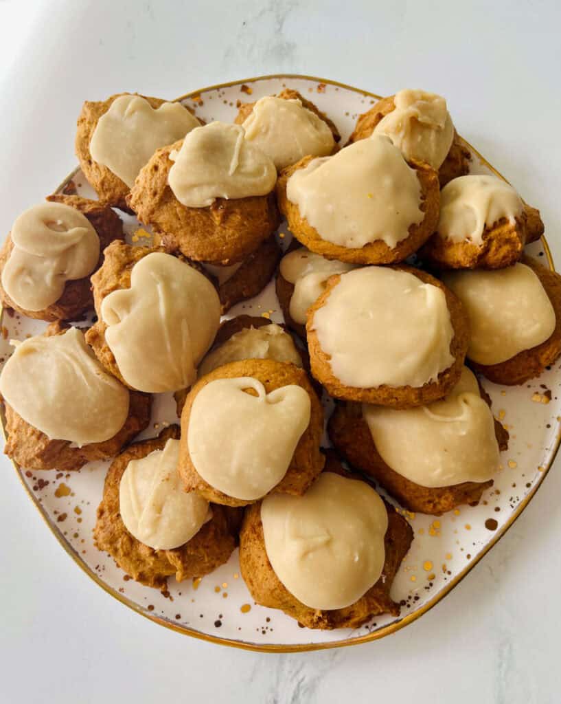 Soft pumpkin cookies with penuche frosting on a decorative plate.