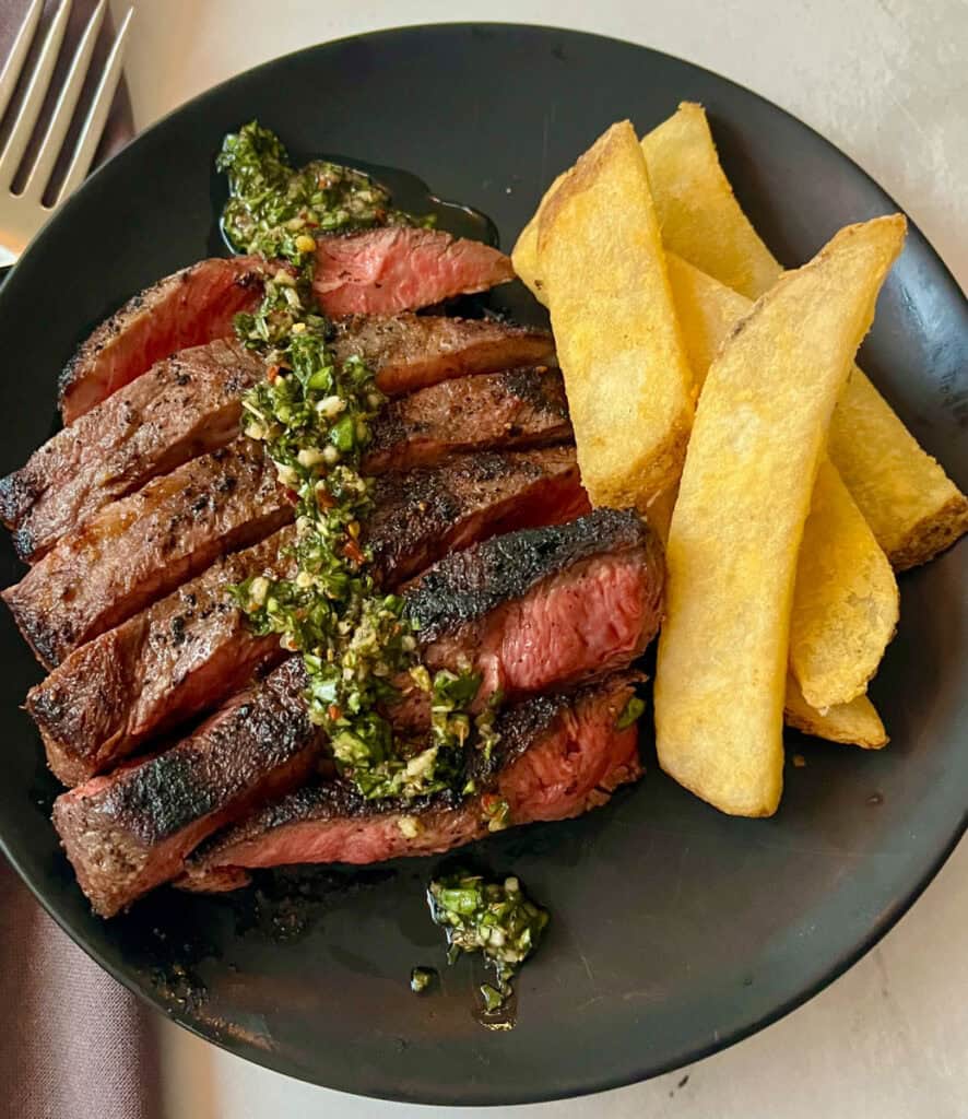 Grilled steak topped with chimichurri sauce served with thick-cut fries.