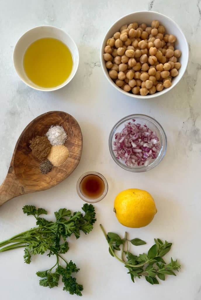 Chickpeas, lemon, herbs, and spices for chickpea salad preparation.