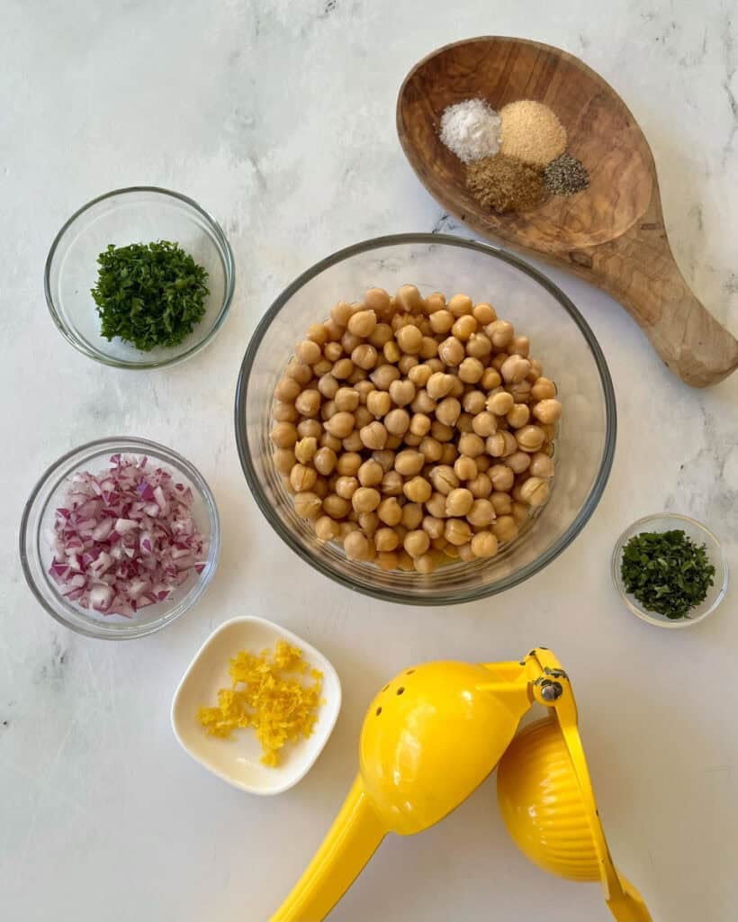 Chickpeas, herbs, spices, and lemon for marinated chickpeas preparation.
