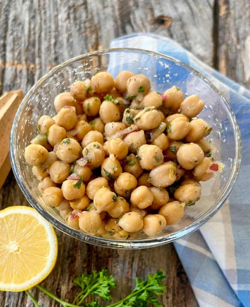 Fresh marinated chickpeas in a glass bowl with lemon and herbs.