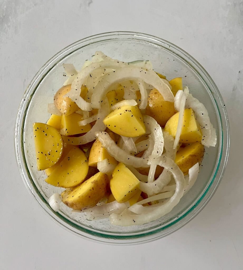 Potato and onion salad in a glass bowl for baking pork chops.