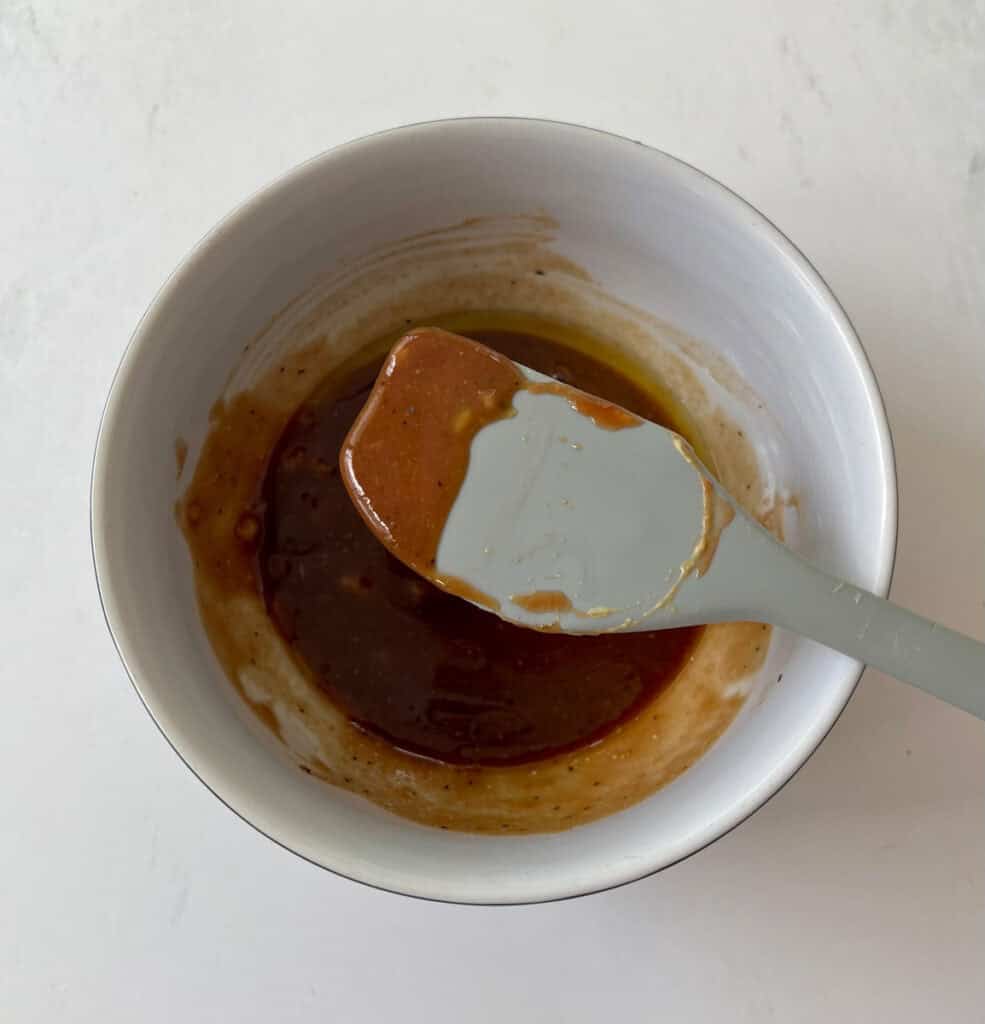 Close-up of homemade sauce in a white bowl with a spoon.